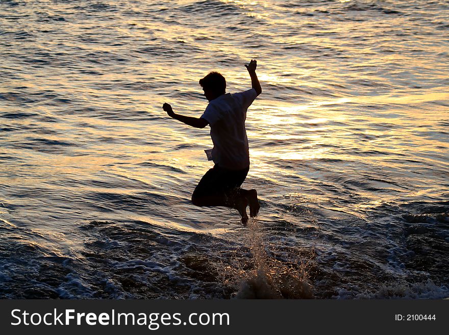 Silhouette of boy jumping in the ocean at sunset. Silhouette of boy jumping in the ocean at sunset