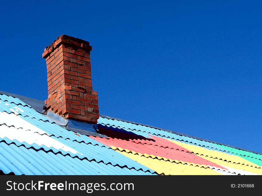 Chimney on colored roof under blue sky