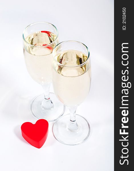 Two glasses of champagne and red plastic heart. Two glasses of champagne and red plastic heart