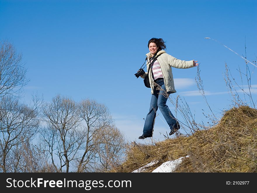 Lady photographer jumping with camera over sunny sky