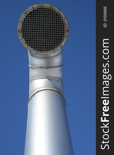 Shiny metallic ventilation pipe with wire mesh on a blue sky background.