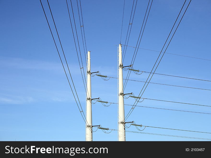 Two white electricity pylons and stretching wires