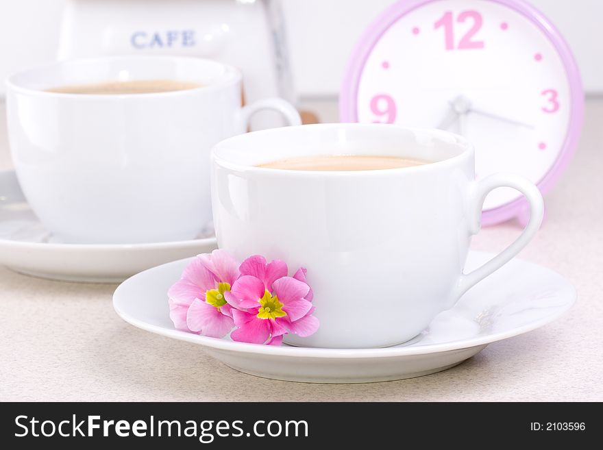 Two cups of coffee (could be a cocoa) and a clock. Two cups of coffee (could be a cocoa) and a clock.