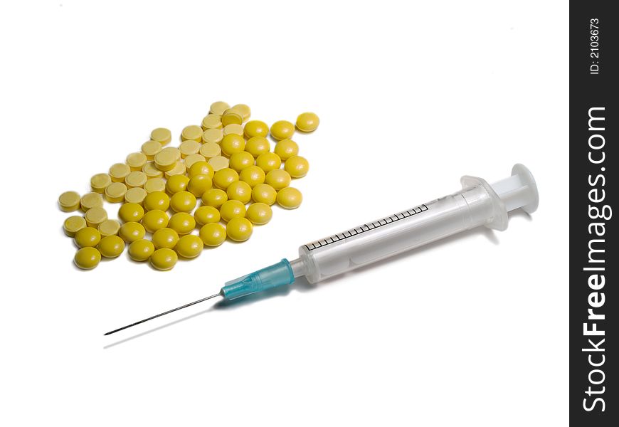 Close-up of syringe and yellow tablets isolated on white