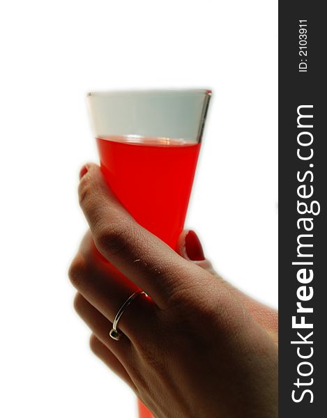 A female hand with red fingernails holding a glass filled with red liquid. A female hand with red fingernails holding a glass filled with red liquid