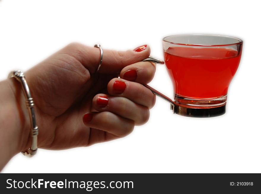 A female hand holding a small glass filled with red liquid. A female hand holding a small glass filled with red liquid