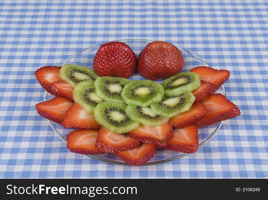 Strawberry, kiwi fruit plate on a blue and white checkerboard cloth