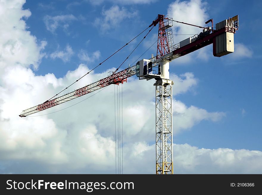 High rise crane with a cloudy blue sky backdrop