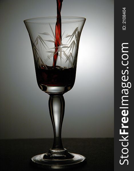 Red wine being poured into a glass. Low key image taken in a studio. Red wine being poured into a glass. Low key image taken in a studio.