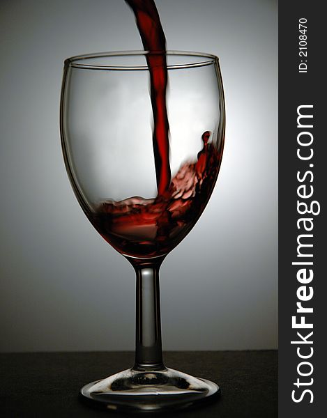 Red wine being poured into a glass. Low key image taken in a studio. Red wine being poured into a glass. Low key image taken in a studio.