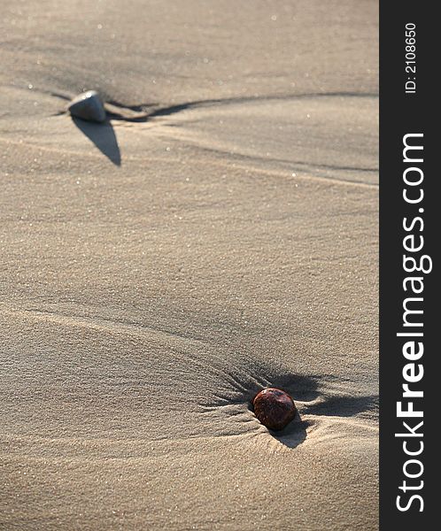 Wet stones in sand on seacoast