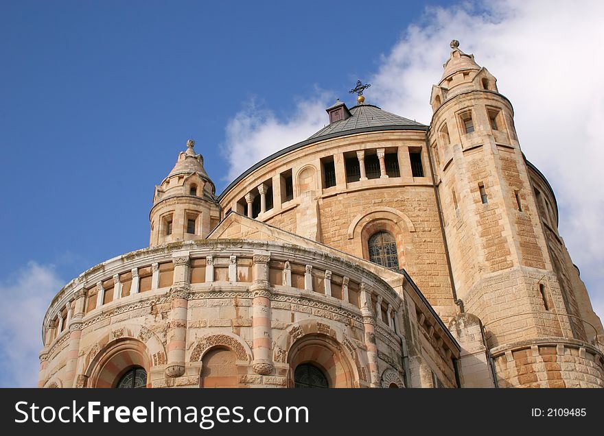 Dormition Abby (Benedictine Basilica of the Dormition) in Jerusalem. The Dormition Abbey is a massive structure, just outside the Zion Gate, and resembles a mighty fortress; it is topped by a high, domed belltower, a conical dome and corner towers.