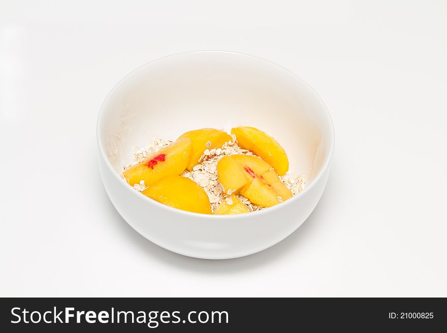 Bowl with oat and peaches on white background