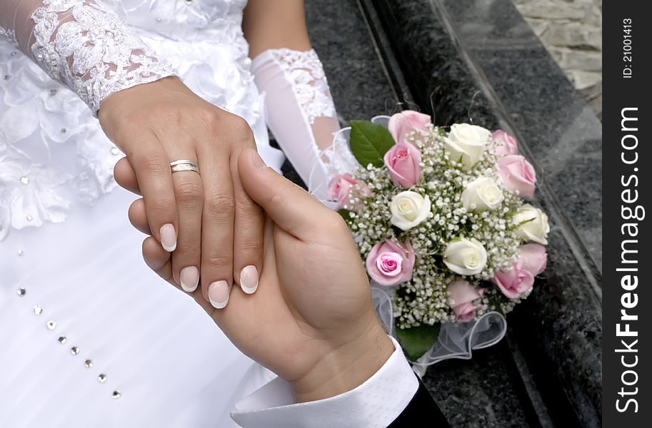 A man holds the hand of woman on a background a bouquet