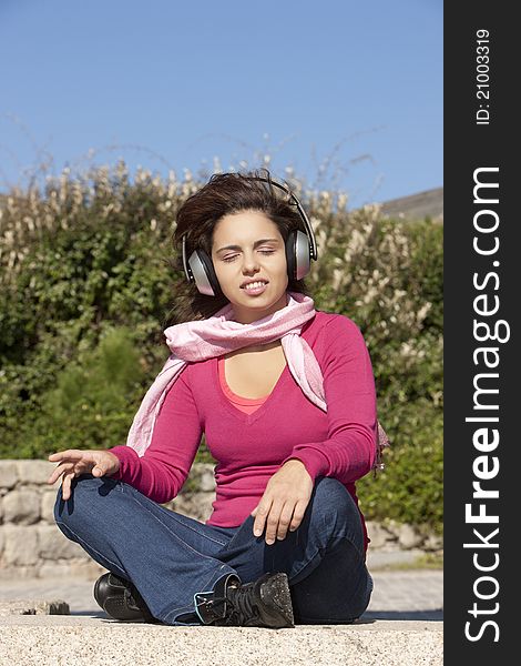 Pretty young girl listening music in the park