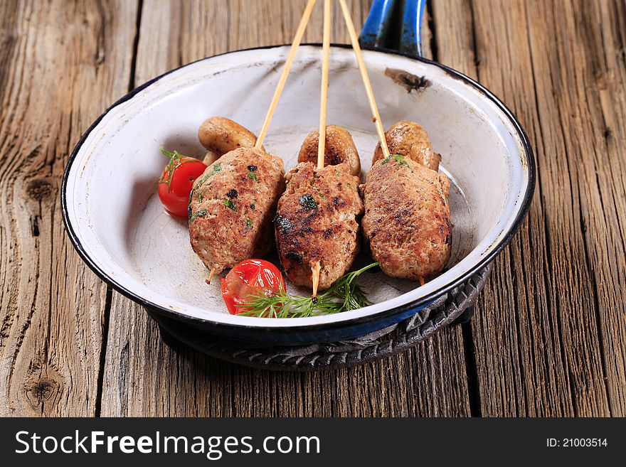 Minced meat kebabs on wooden skewers and mushrooms