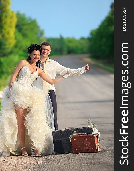 Newlywed Couple Hitchhiking On A Road