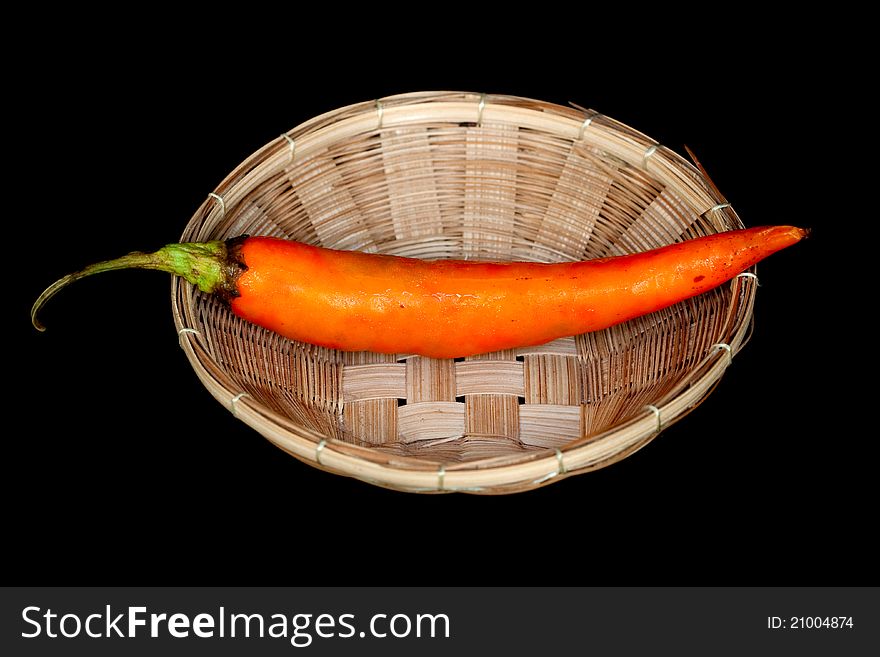 Orange sweet pepper in small basket on black background