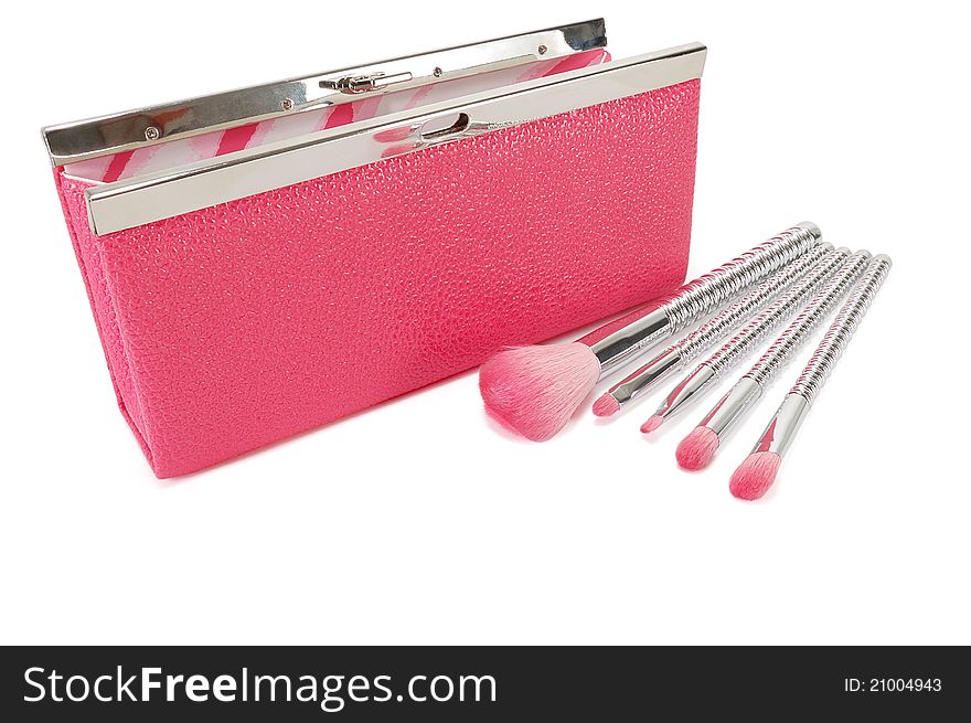 Pink handbag and cosmetic brushes on a white background