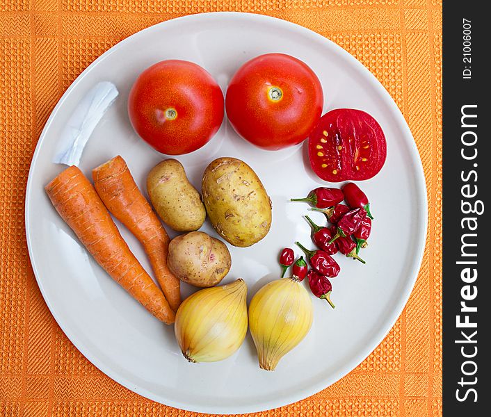 Fresh vegetables at white plate on orange. Fresh vegetables at white plate on orange