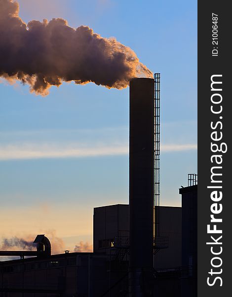 Industrial factory with smoking chimney at sunset. Industrial factory with smoking chimney at sunset