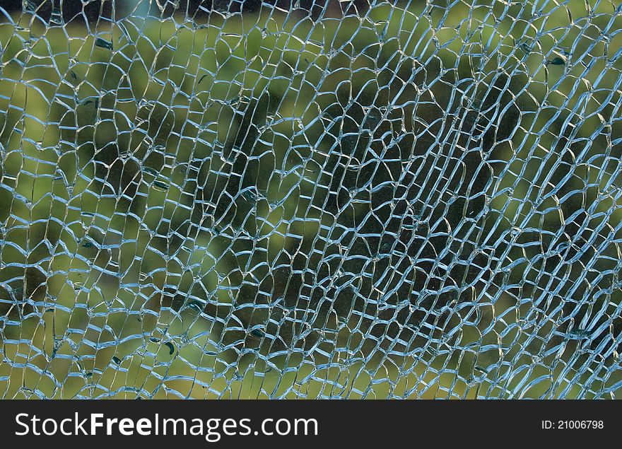 A view through a broken glass with beautiful green colors in the background