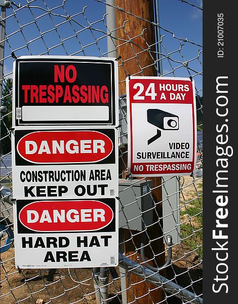 Four warning signs attached to a chain link fence