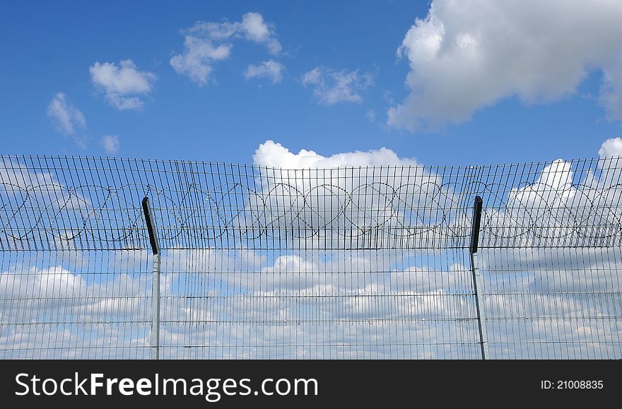 Blue sky behind a fence with barbed wire. Blue sky behind a fence with barbed wire