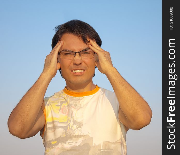 Portrait of young angry man against blue sky. Portrait of young angry man against blue sky