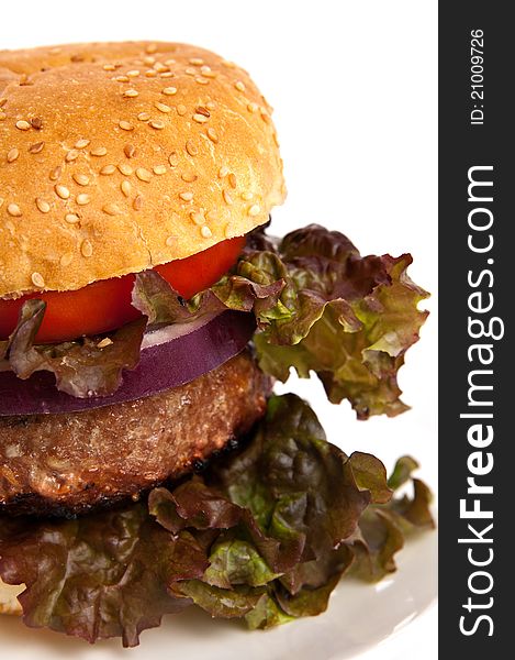 Close up of a hamburger with lettuce, tomato and purple onion isolated on white.