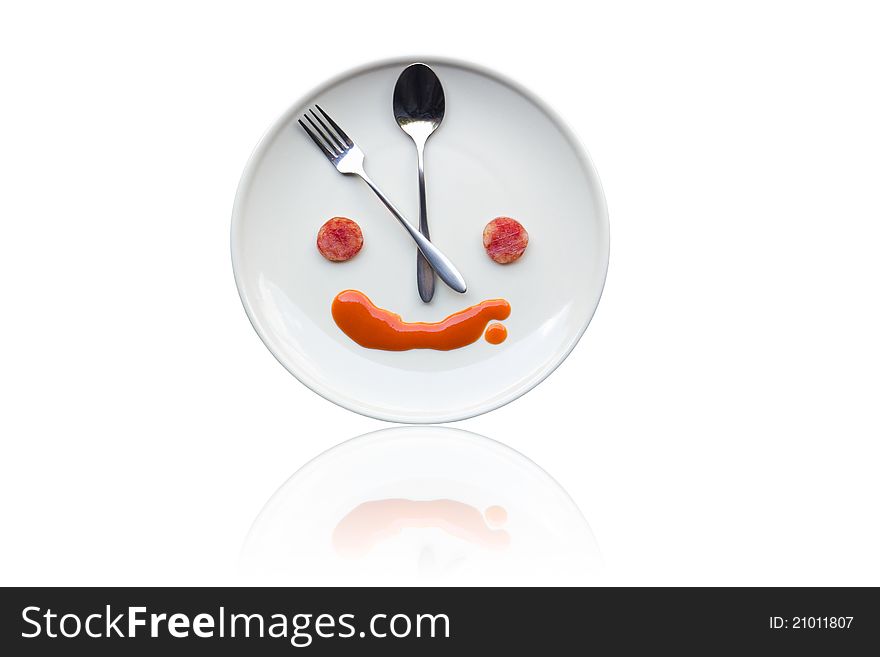 Metal spoon and fork arrange as clock face on white dish with artistic human like face from food