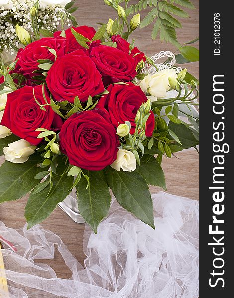 Studio-shot of a bridal bouquet with red and white roses on a wooden tray.