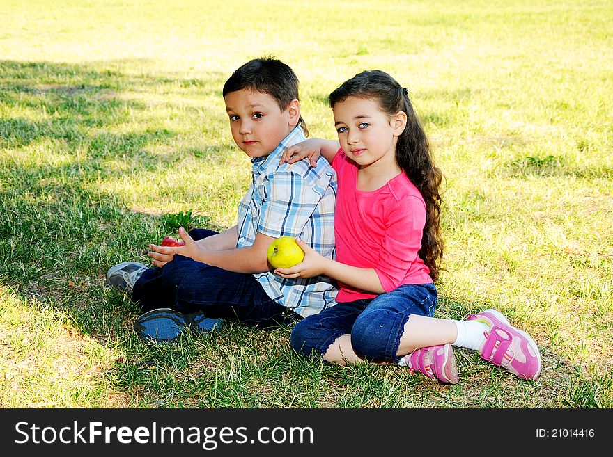 The boy with the girl play sitting on a grass in park