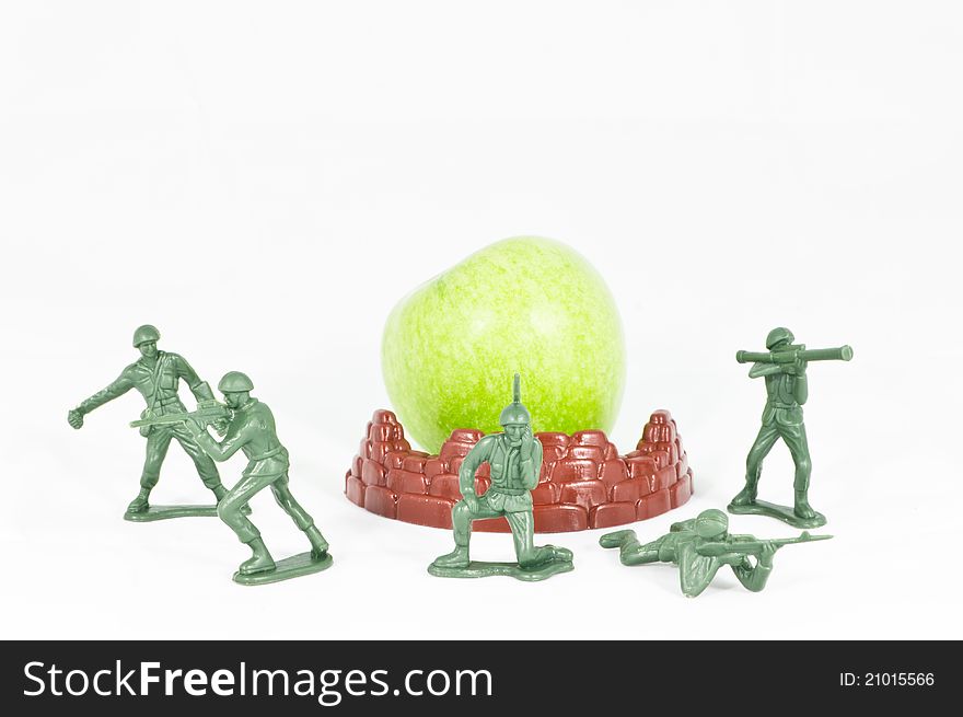 Front view of a group of soldier toy protecting a green apple. Front view of a group of soldier toy protecting a green apple