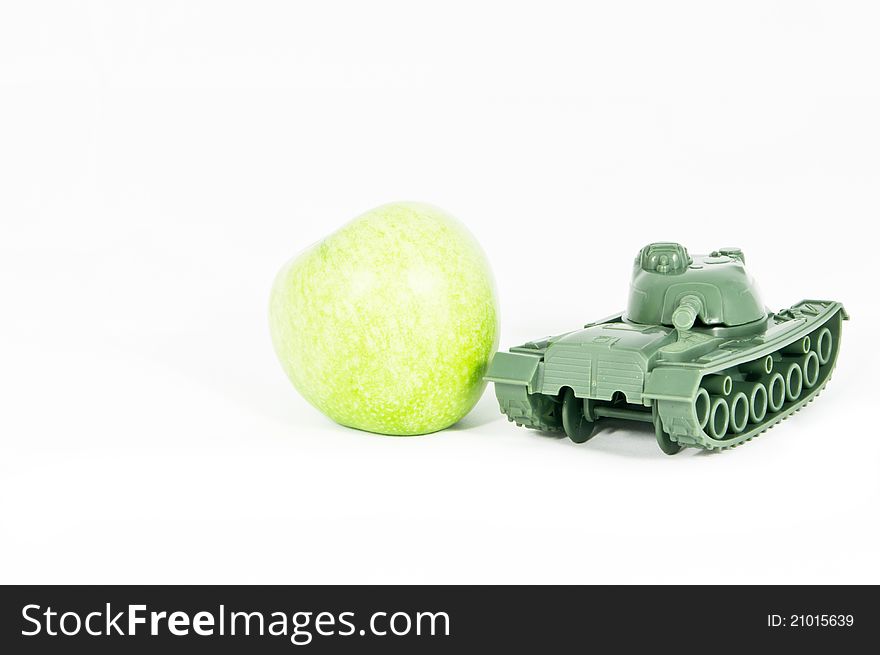 Front view of a toy tank protecting a green apple. Front view of a toy tank protecting a green apple