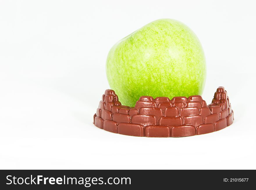 Front view of a green apple protected by a toy fortification. Front view of a green apple protected by a toy fortification
