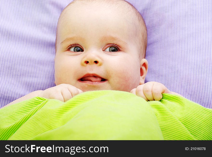 Baby looking out from under blanket