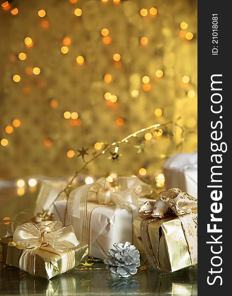 Close-up of gift boxes with ribbon,cone and blurred lights on gold background. Close-up of gift boxes with ribbon,cone and blurred lights on gold background.