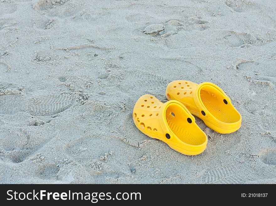 Bright yellow flip-flops on sand beach