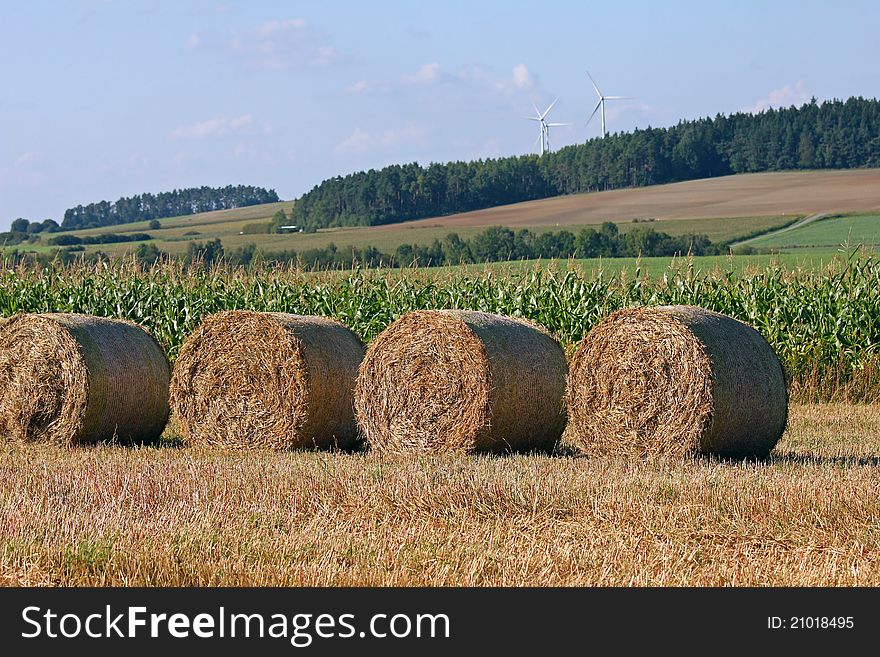 Bale of straw with wind turbine and forest in the background