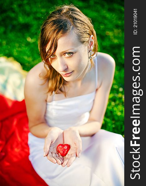 Newlywed woman holding in her hands red heart - symbol of love. Newlywed woman holding in her hands red heart - symbol of love