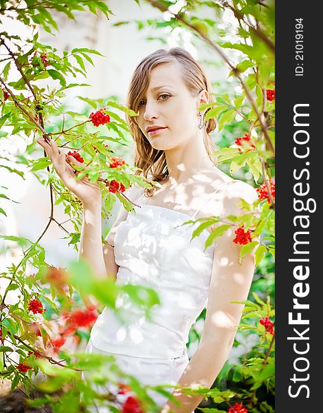 Portrait of a pretty bride standing near the tree with red berries