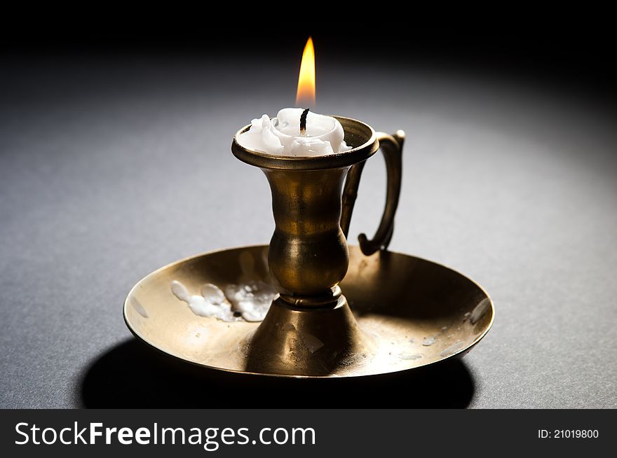 Burning candle in a brass candlestick with streaks
