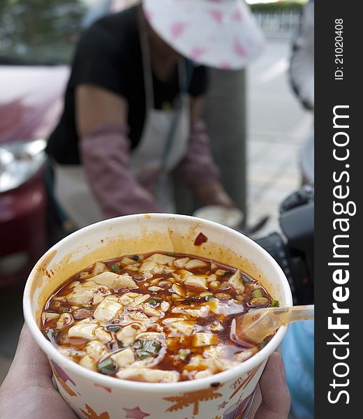Delicious Sichuan bean curd and street hawker as background