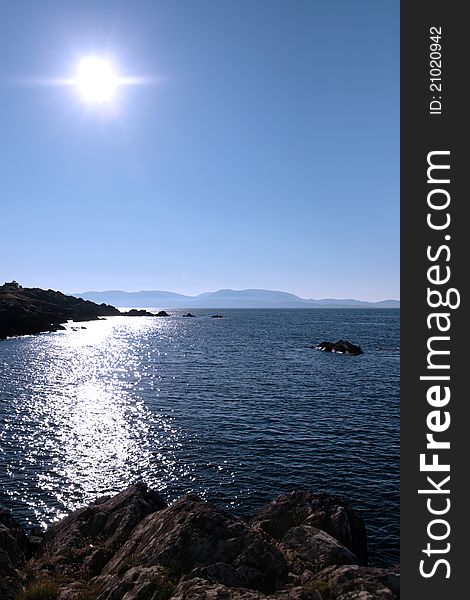Scenic view in kerry ireland of rocks and sea with mountains against a beautiful bright sunny sky. Scenic view in kerry ireland of rocks and sea with mountains against a beautiful bright sunny sky