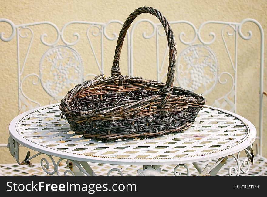 Decorative wicker basket on white metal table in home garden