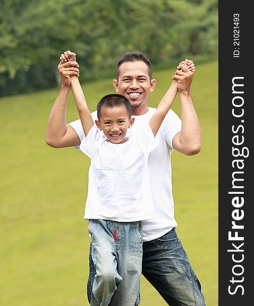 Man and young boy outdoors playing airplane smiling in the park. Man and young boy outdoors playing airplane smiling in the park