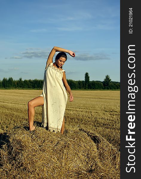 Girl in a rural clothing standing on the haystack. space for text