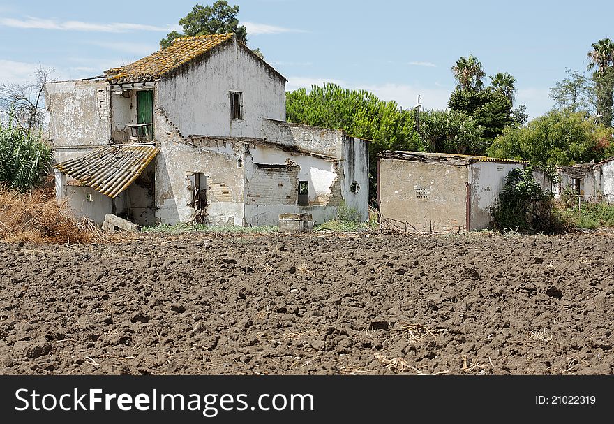 Rural two-story house in ruins at the foot of a field without sowing. Rural two-story house in ruins at the foot of a field without sowing