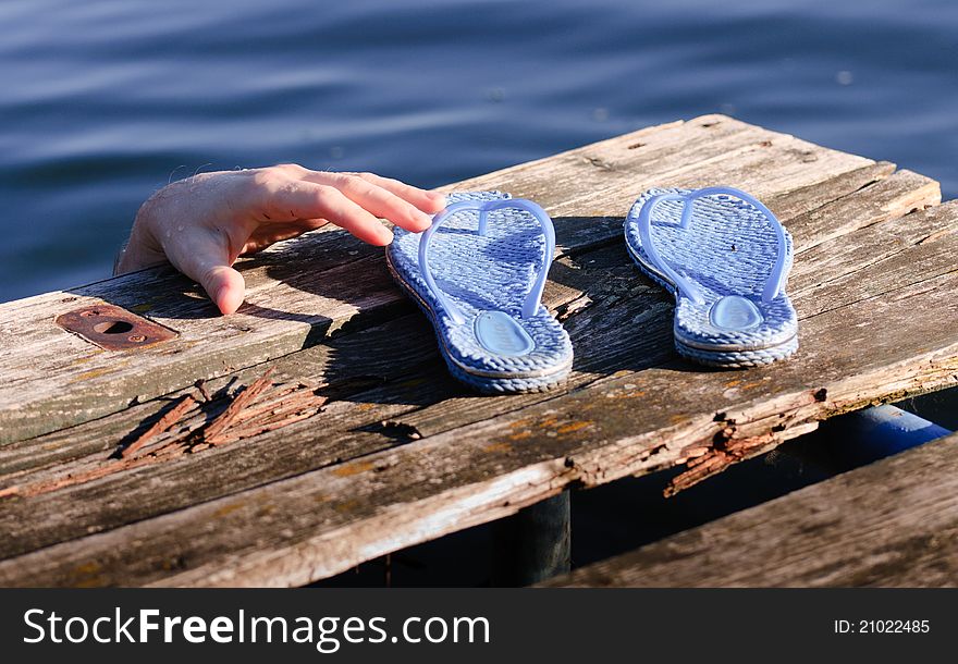Blue sandal on the pier with hand. Blue sandal on the pier with hand
